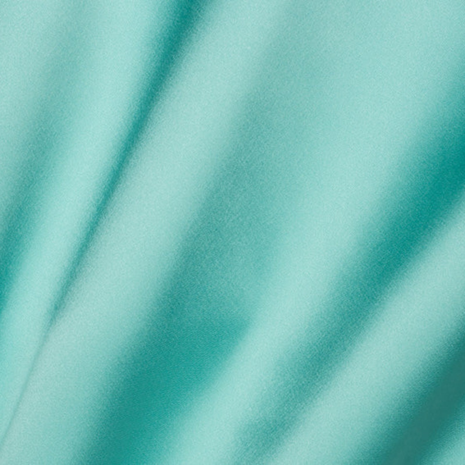 A close-up of draped mint green fabric with soft folds and a smooth texture.
