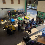 View from above of the entry level at Barley Pop, with Mindy standing beside her dog Jasper while people gather at tables for Stitch ’n Bitch.