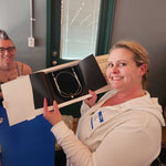 A Stitch ’n Bitch prize winner holding a box of circular knitting needles at Barley Pop Brewing.