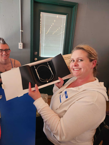 A Stitch ’n Bitch prize winner holding a box of circular knitting needles at Barley Pop Brewing.