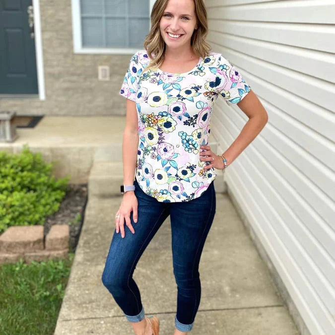 Outdoor view of the Sulky Perfect Tee sewn in a floral print with short sleeves, worn with jeans on a front‑walkway setting