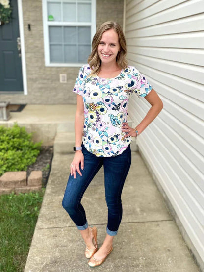 Outdoor view of the Sulky Perfect Tee sewn in a floral print with short sleeves, worn with jeans on a front‑walkway setting