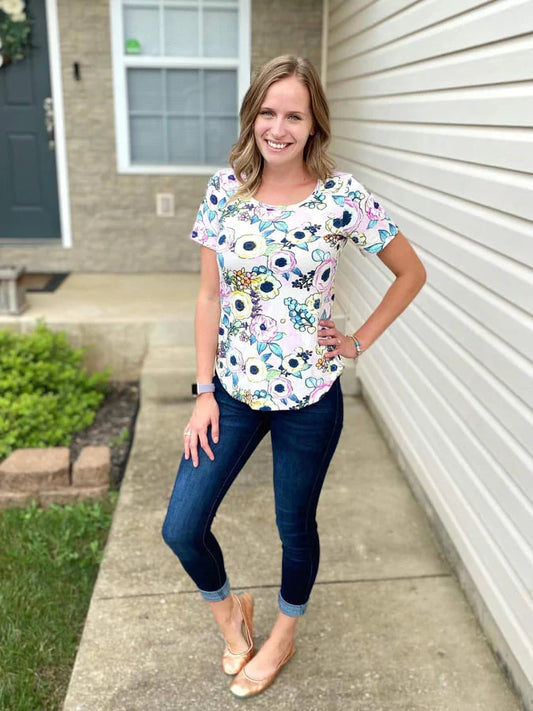 Outdoor view of the Sulky Perfect Tee sewn in a floral print with short sleeves, worn with jeans on a front‑walkway setting