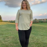 Outdoor view of the Sulky Perfect Tee sewn in a light striped knit with three‑quarter sleeves, worn with black pants in a wide grassy field at sunset
