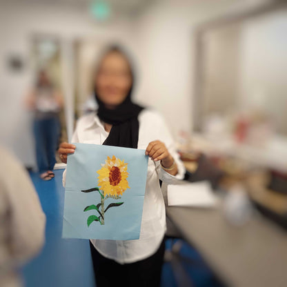 Student displaying their finished sunflower collage block created using the parchment pressing technique.