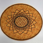 Round orange trivet with a stitched geometric sunflower design in black embroidery.