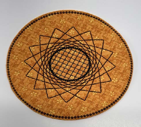Round orange trivet with a stitched geometric sunflower design in black embroidery.