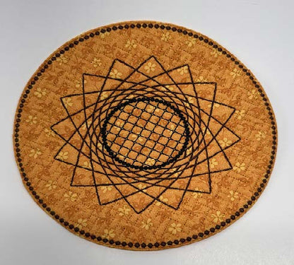 Round orange trivet with a stitched geometric sunflower design in black embroidery.