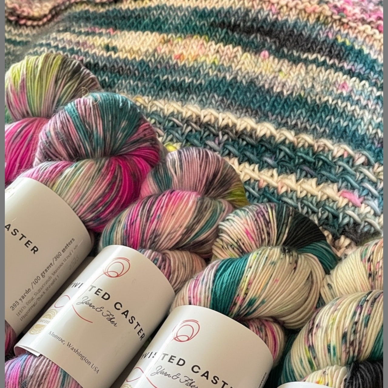 Hand‑dyed multicolored yarn with a coordinating knitted swatch in the background.