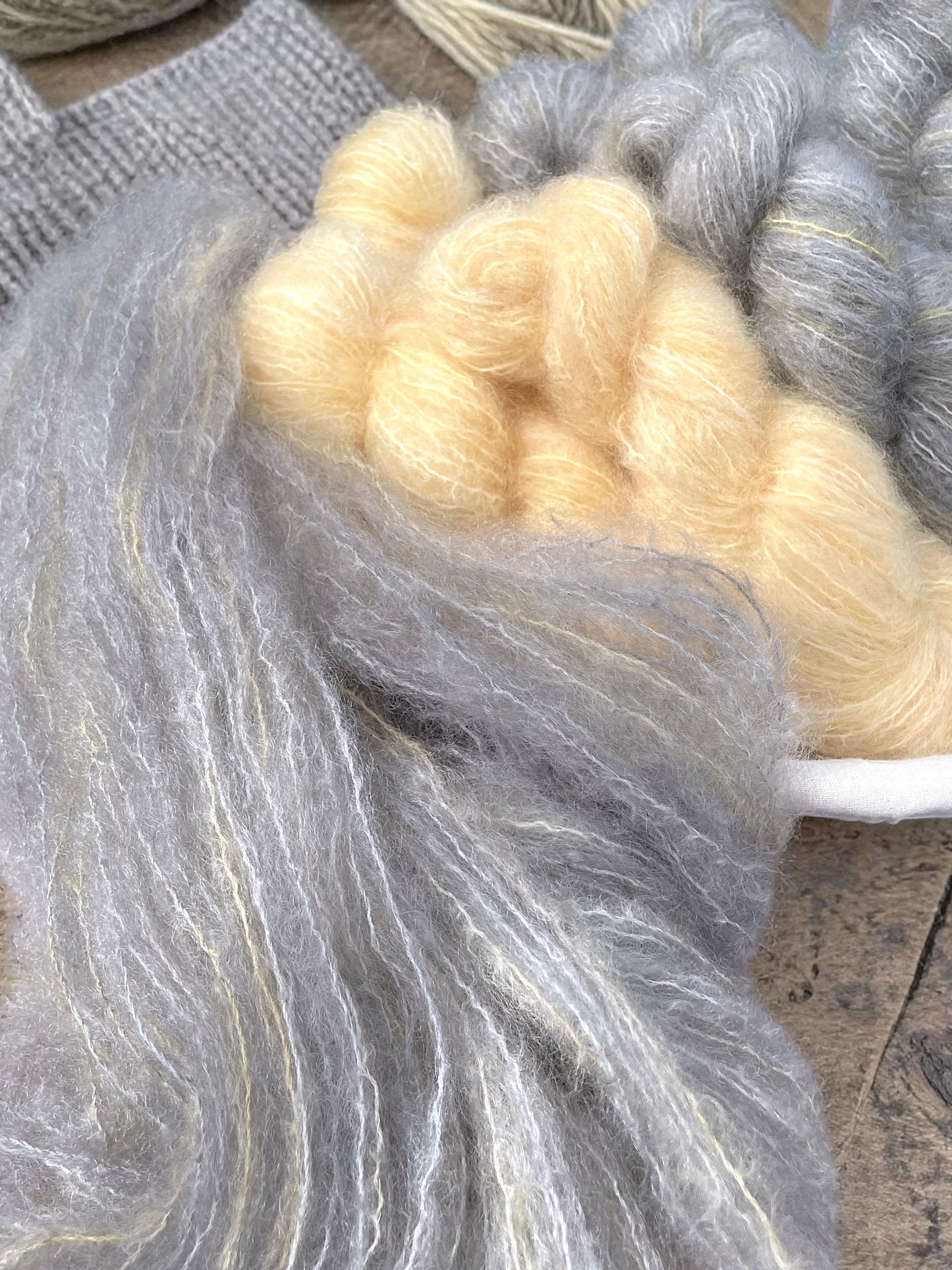 Hand-dyed DK mohair fluff in soft gray and pale yellow tones.