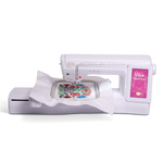 A white sewing machine with a digital display screen on the right side, shown with a white fabric arm holding a colorful floral embroidery pattern.
