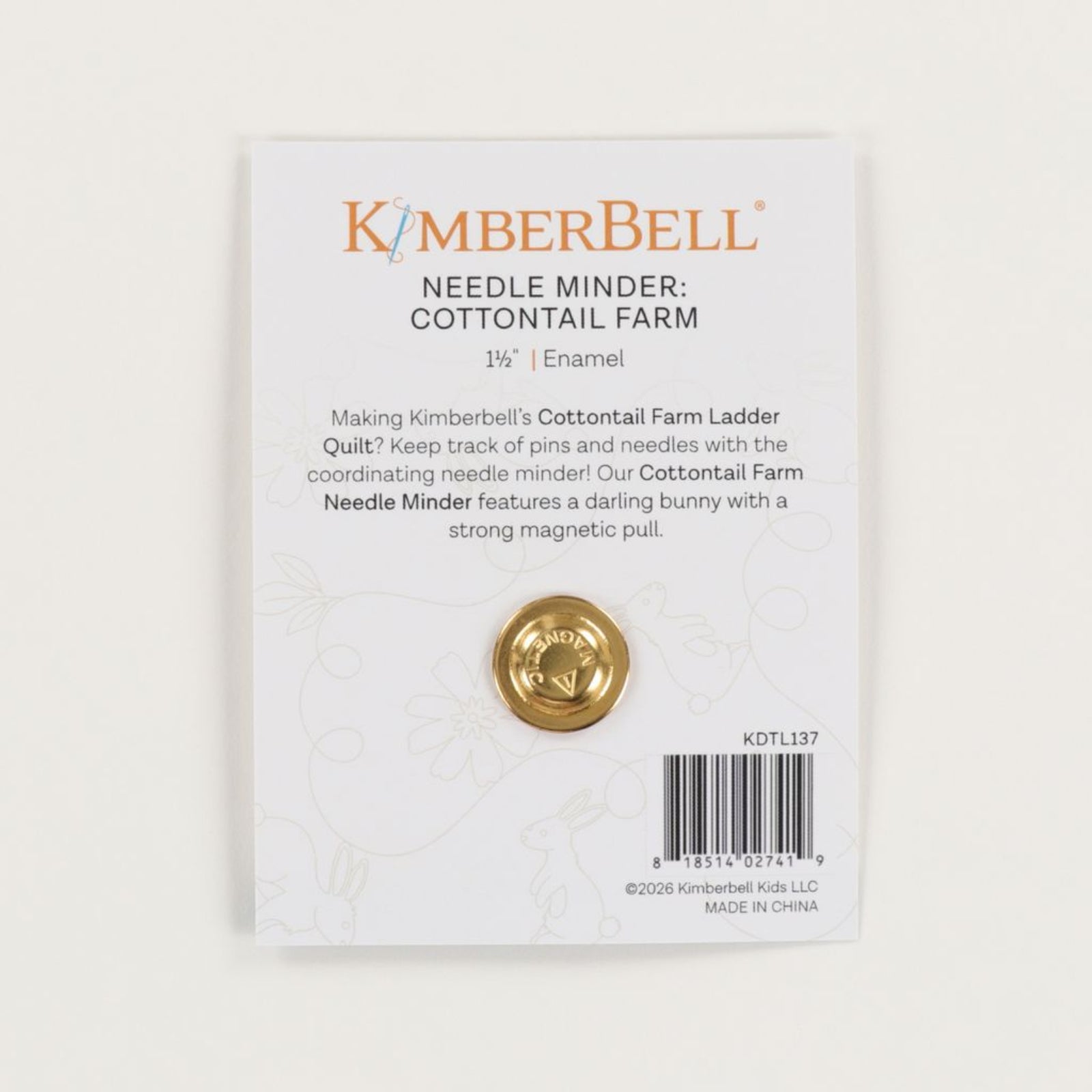 KimberBell Needle Minder: Cottontail Farm enamel pin on its original backing card. The card is white with gold and orange text, featuring a gold-colored circular pin with a bunny cutout in the center.